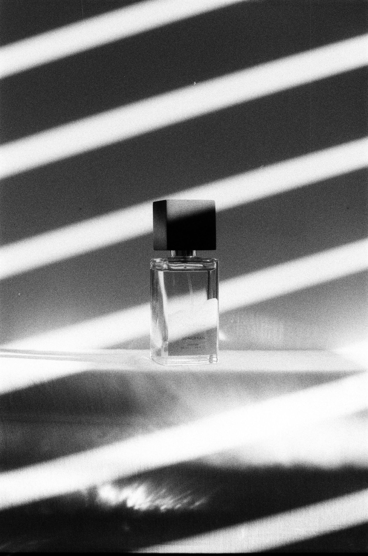 Frasco de perfume sob luz de persiana